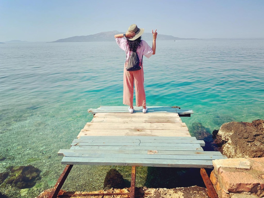 Girl standing on makeshift pier overlooking the Ionian Sea from Albania.